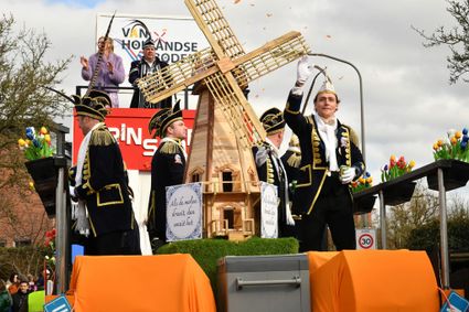 Praalwagen met houten molen en tulpen tijdens carnaval in Oudewater, begeleid door feestelijk geklede deelnemers in kostuums – een typisch Hollands tafereel in het Groene Hart.