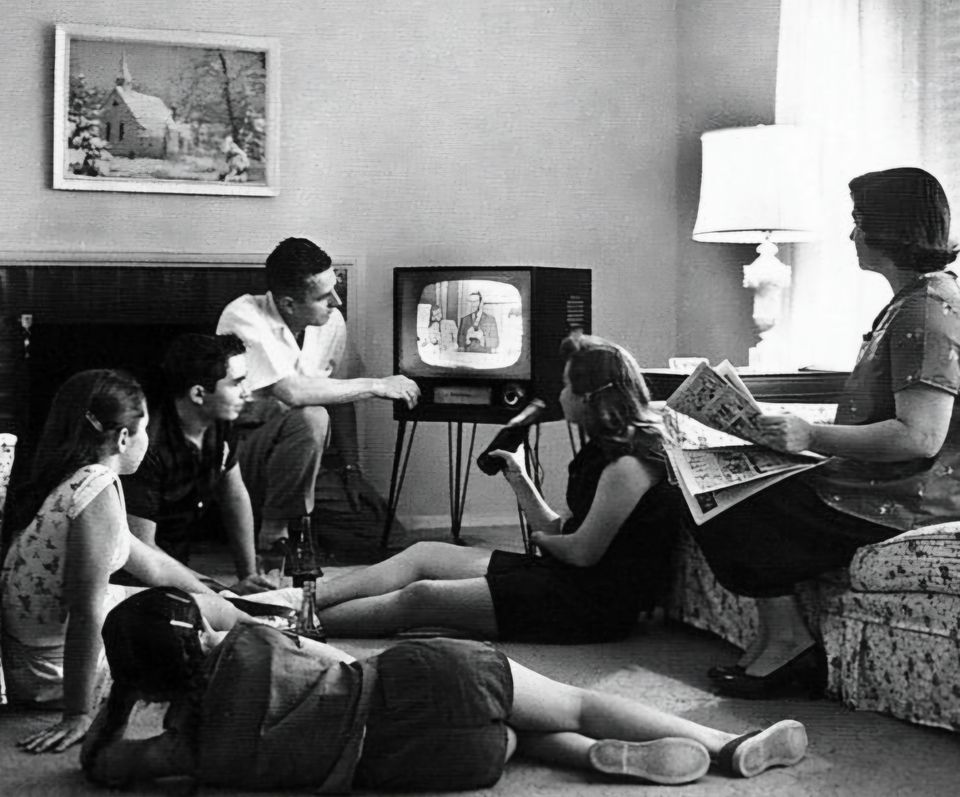 Zwart wit foto waarop een gezin samen naar een televisie uitzending kijkt