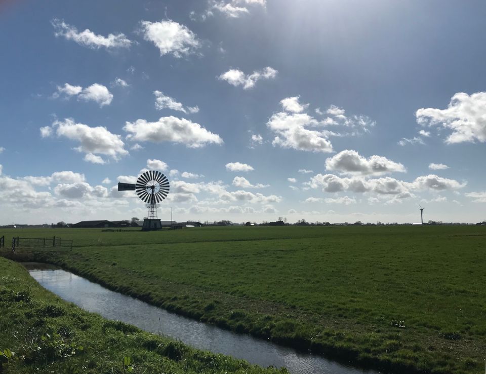 molen in een weiland en blauwe lucht met een paar kleine wolkjes