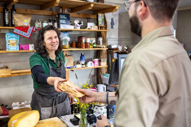 Kaas wordt overhandigd in boerderijwinkel door medewerker