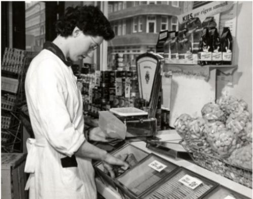 Een zwart-wit foto van een medewerker in de eerste winkel van Albert Heijn