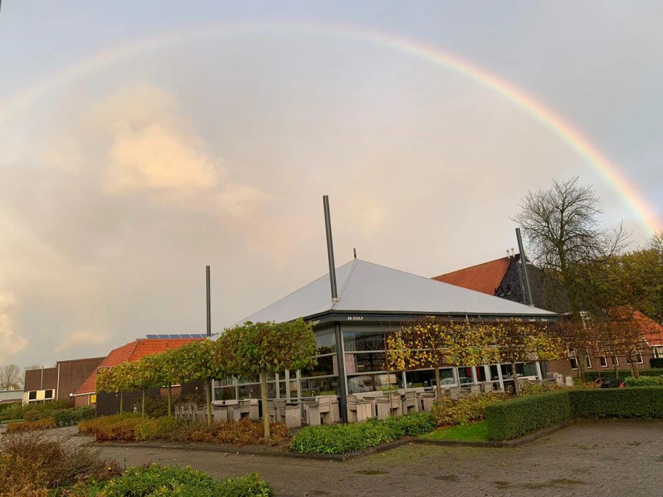Voorkant van Sport Restaurant De Stolp met regenboog in de lucht