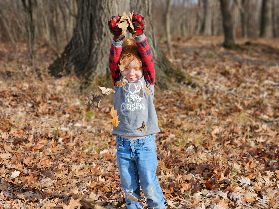 Kind speelt met herfstbladeren