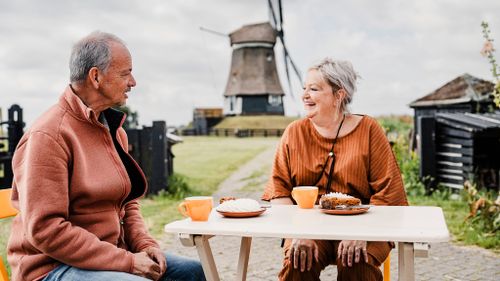 Twee mensen die een taartje eten en koffie drinken bij De Breek