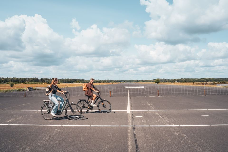 Fietsers op de voormalige landingsbaan van Park Vliegbasis Soesterberg. De foto laat de bijzondere combinatie van fietsen, open landschap en het militaire verleden van het gebied zien.