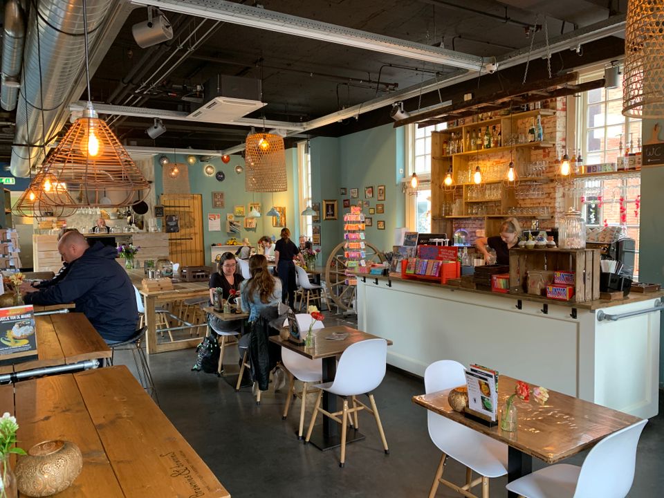 Restaurant Brownies & downieS in Woerden, Groene Hart, sfeervol interieur met houten tafels, kleurrijke inrichting, open bar en gasten die binnen eten en drinken.