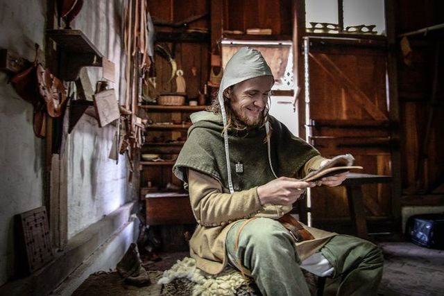 Middeleeuwse leerbewerker aan het werk in een ambachtelijke werkplaats in Archeon, gekleed in historische kleding en omringd door handgemaakte voorwerpen.