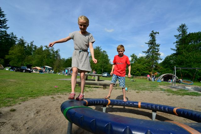 Kinderen spelen op een speeltoestel in de speeltuin van Allurepark De Zeven Linden in Baarn. De foto laat de kindvriendelijke sfeer en recreatiemogelijkheden op de camping zien.