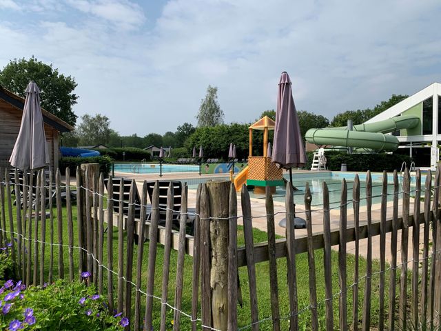 Uitzicht op het buitenzwembad van vakantiepark EuroParcs in Kaatsheuvel met op de achtergrondeen waterglijbaan