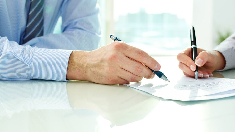 Two people signing a form.