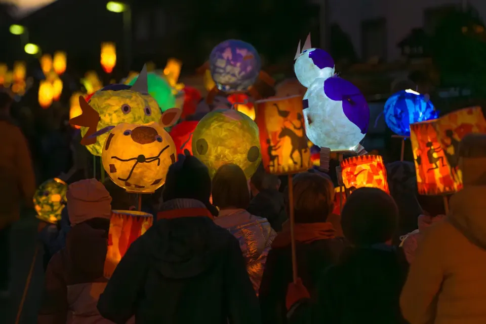 a bunch of children walking at night with handmade paper lanterns