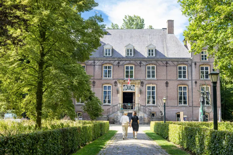 Twee wandelaars lopen op de oprijlaan van Kasteel Nemerlaer Haaren