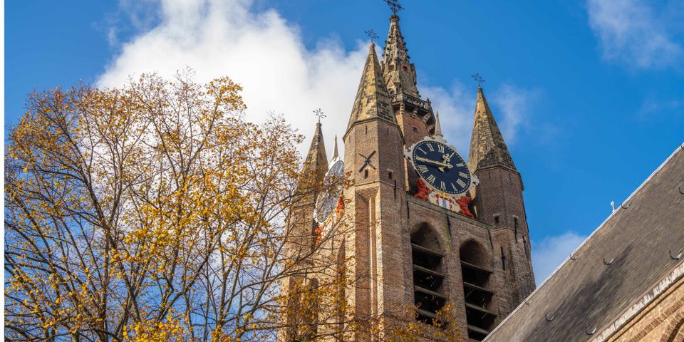 De Oude Kerk van Delft met herfstbladeren