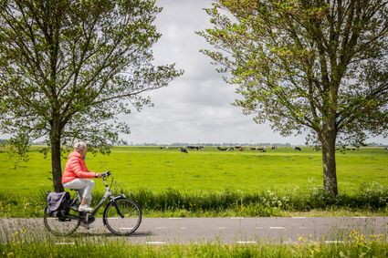 Vrouw met roze jas op de fiets