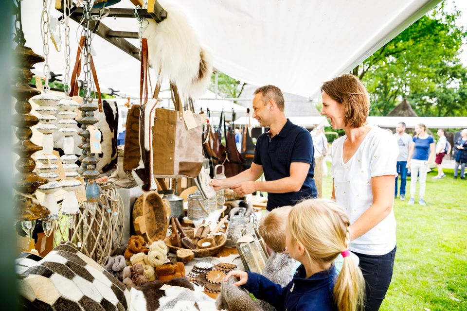 Gezin staat bij een kraampje te kijken op de markt.