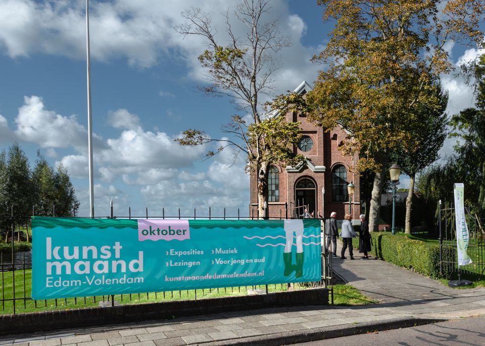 Een foto van het kerkje in Middelie met een spanddoek van de Kunstmaand
