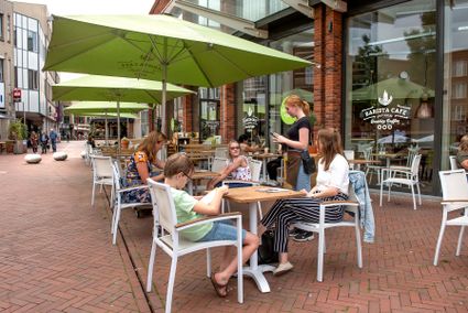 Mensen zitten op het terras van een restaurant te eten en drinken en te kletsen met elkaar.