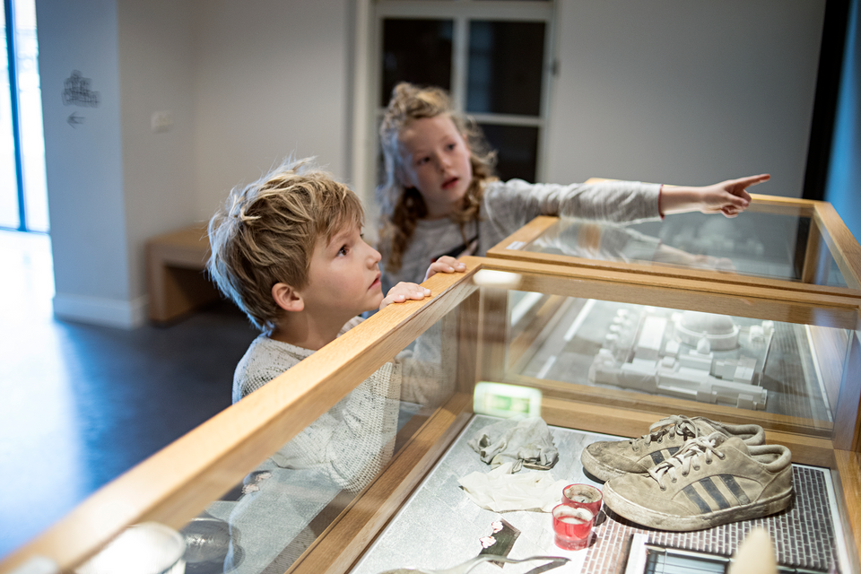 Ein Junge und ein Mädchen schauen sich interessiert alle Attribute im Gefängnismuseum an.