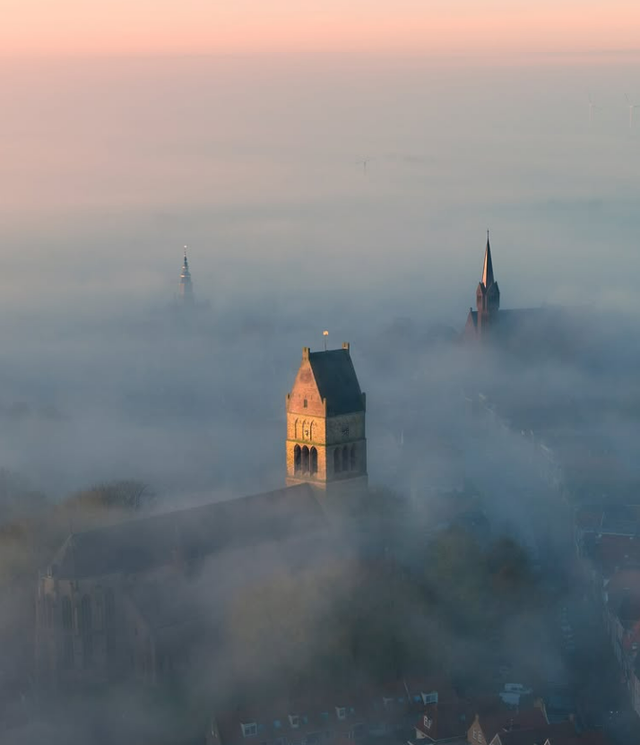 Bolsward vanuit de lucht. Kerktorens boven de mist.