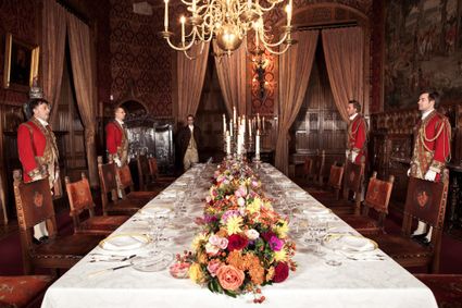 Historische dinertafel in Kasteel de Haar met bloemstuk, kaarsen en personeel in uniform, cultureel erfgoed in het Groene Hart.