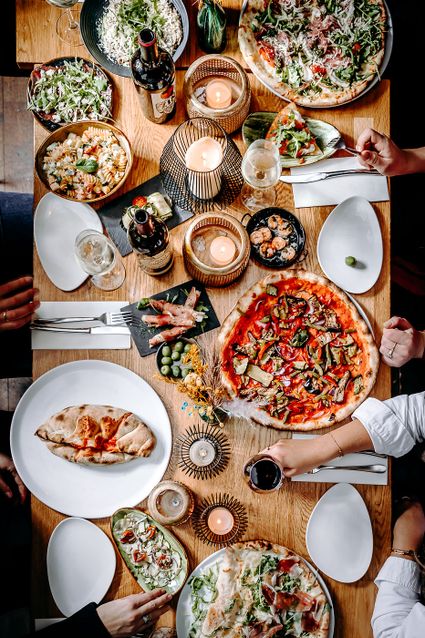 Afbeelding van restaurant Aperitivo met tafel gedekt met pizza erop en pasta