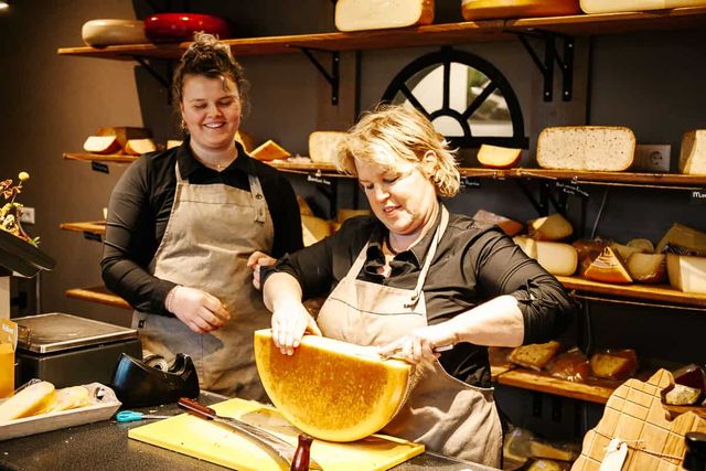 Twee vrouwen waarvan één kaas aan het schaven is.