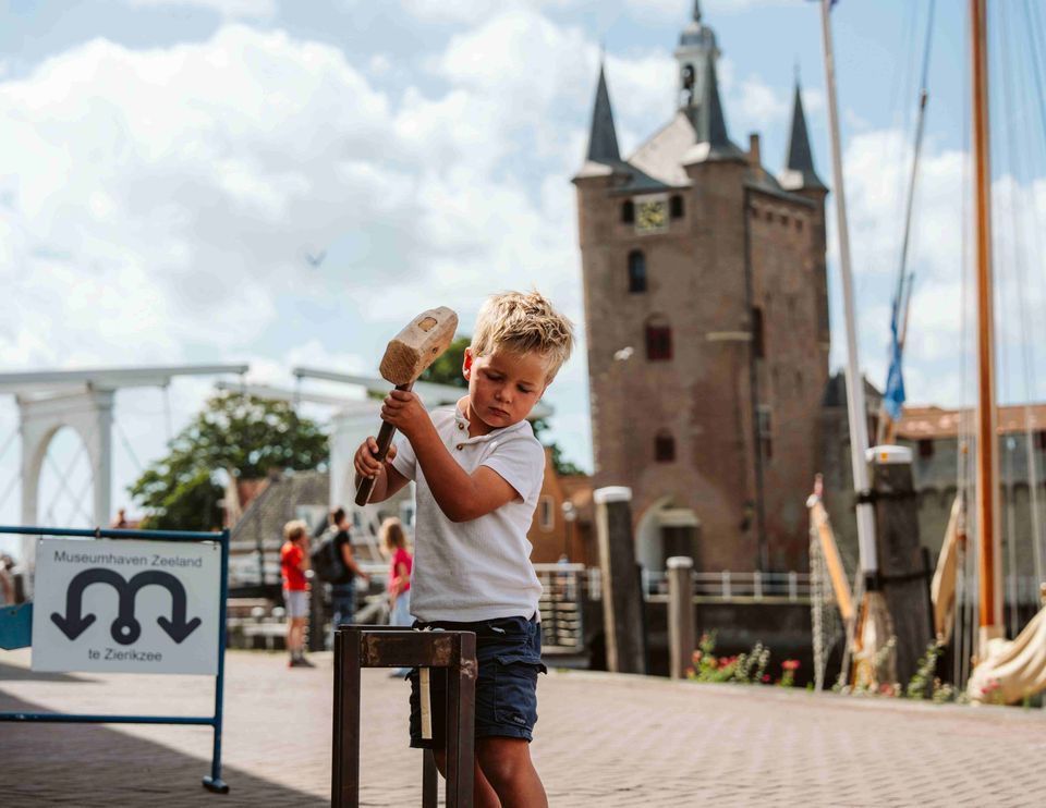 Kind slaat met hamer op spijker bij Museumhaven in Zierikzee