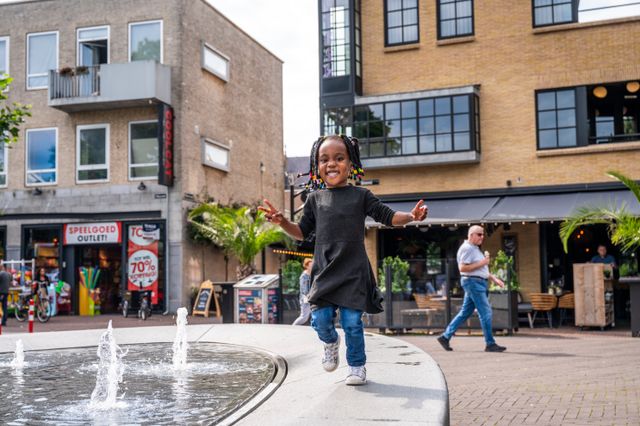 Kind speelt bij waterfontein in het centrum van Oss
