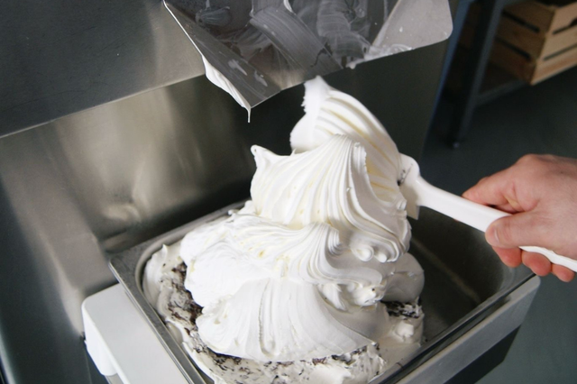 Das Eis kommt aus der Eismaschine und wird in einen Behälter gefüllt.