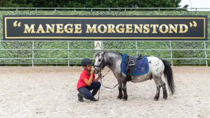 Kind met helm en pony tijdens een paardrijles op de open dag bij Manege Morgenstond in Woerden.