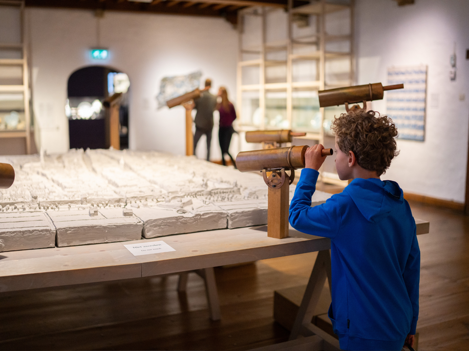 Jongen genaamd Rick die door vergrootglazen kijkt in het Museum Prinsenhof Delft