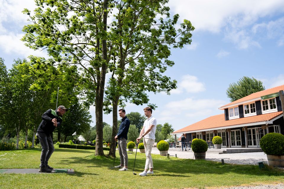 Twee deelnemers volgen een golfclinic bij Buitenplaats Kameryck in het groene landschap van het Groene Hart.