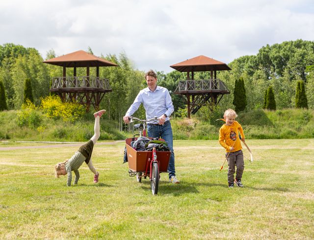 Een vader en twee kinderen in Park Matilo, met twee wachttorens op de achtergrond.
