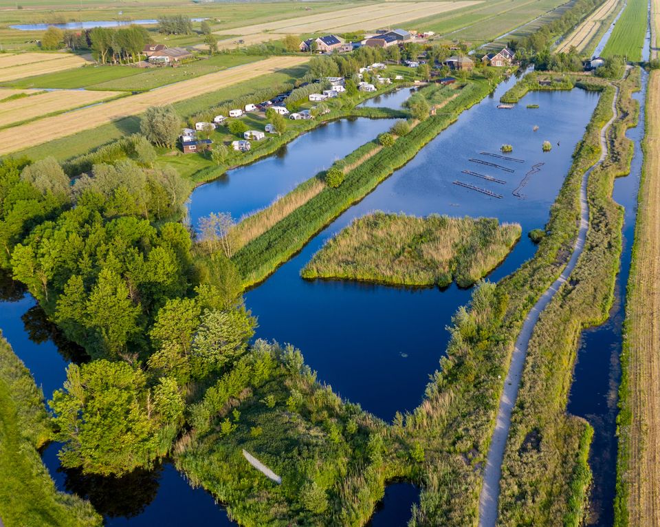 Een bovenaanzicht van het Ijsvogelpad in het Zaanse Rietveld waar je veel natuur zoals bomen en water.