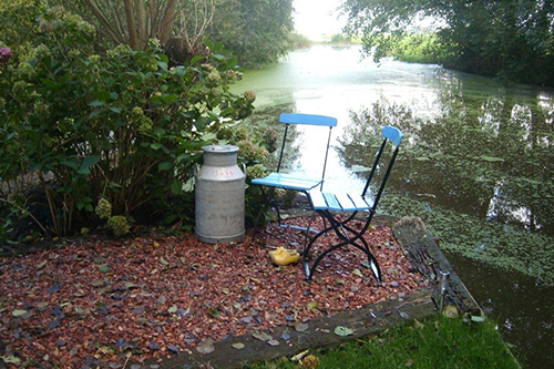 Rustige zitplek aan het water bij B&B Hortensia Eiland in het Groene Hart met stoelen in het groen, idyllische plek om te ontspannen, genieten van natuur, stilte en een comfortabel verblijf in een landelijke omgeving.