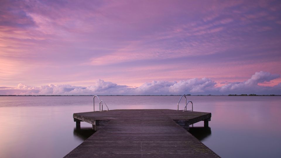Een bizar paars belichte foto van een steiger aan het windstille Tjeukemeer