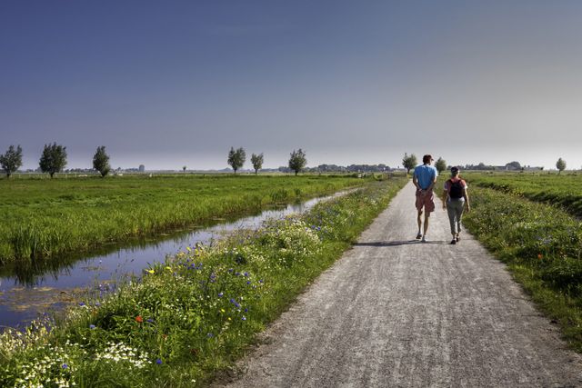 Twee mensen lopen over een pad door de polders.