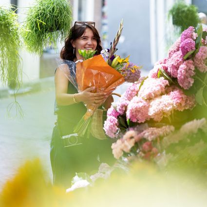 UItblinker Choe met bloemen in de hand op de markt