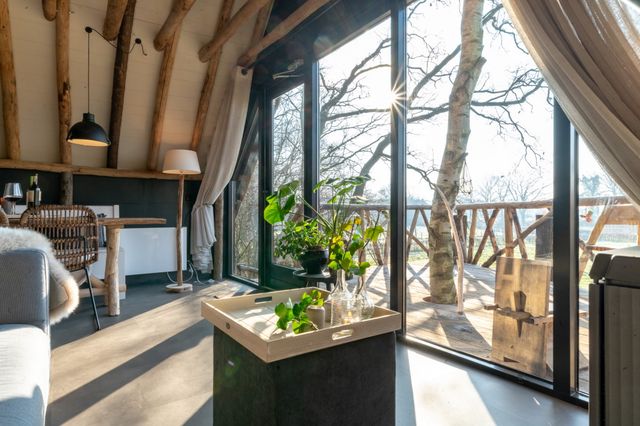 De binnenkant van een boomhut met zicht op het balkon.