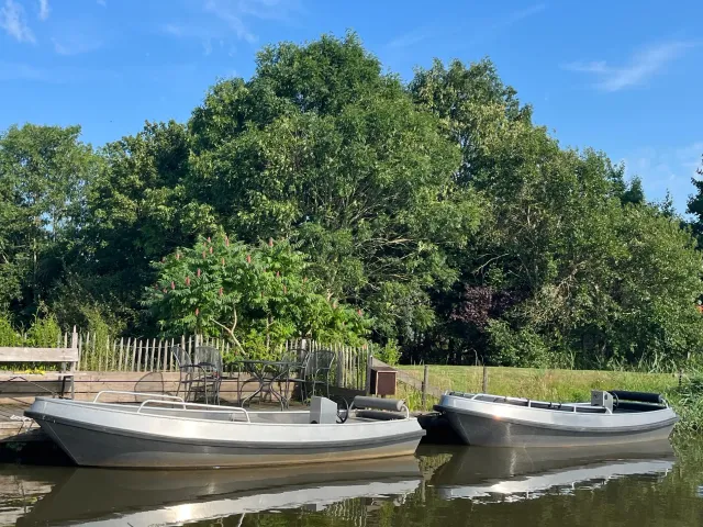 Twee bootjes in het water aan het terras bij Villa Romsicht in Heeg.