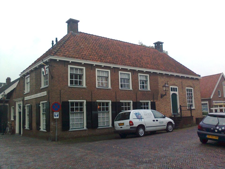 Buitenaanzicht van Het Wapen van Linschoten met een witte auto ervoor geparkeerd.