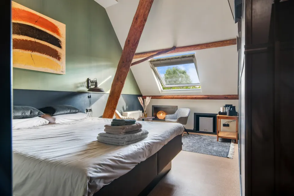 Een tweepersoonsbed in een kamer met houten balken aan het plafond bij B&B Langweer.