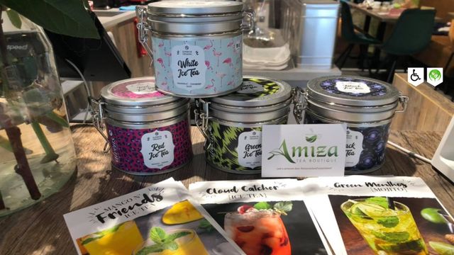 Speciaalzaak Amiza Tea Boutique Woerden, provincie Utrecht, Groene Hart, blikjes met losse thee en kaarten met ijsthee recepten op houten tafel in de theewinkel in het centrum.