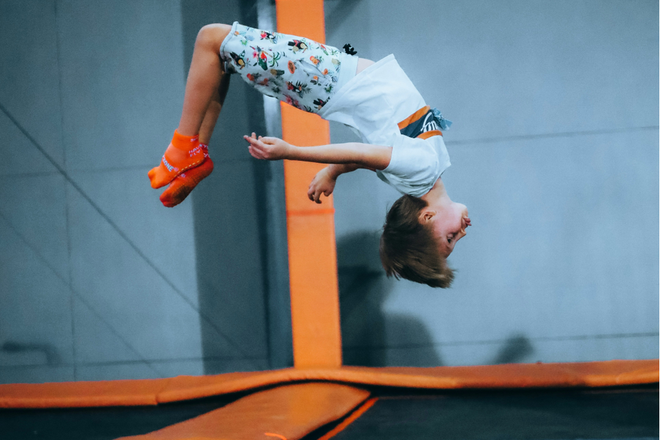 Een jongetje maakt een salto achterover op een trampoline.