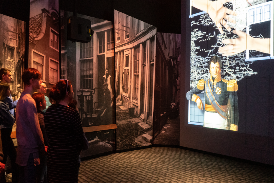 Mensen kijken naar een projectie in museum de Proefkolonie.