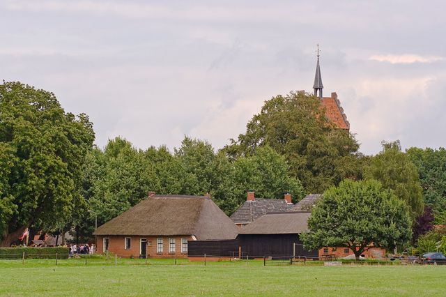 Dorpsaanzicht met boerderijen en een kerktoren.