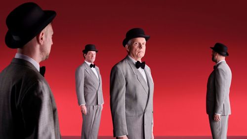Mannen met in pak met een hoed op, op een rode achtergrond