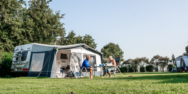 Mensen zittend voor hun tent bij camping Hoeve Bouwlust