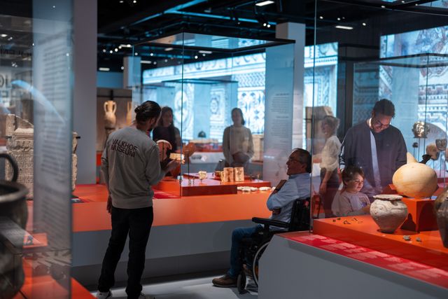 Diverse mensen kijken naar voorwerpen in twee vitrines
