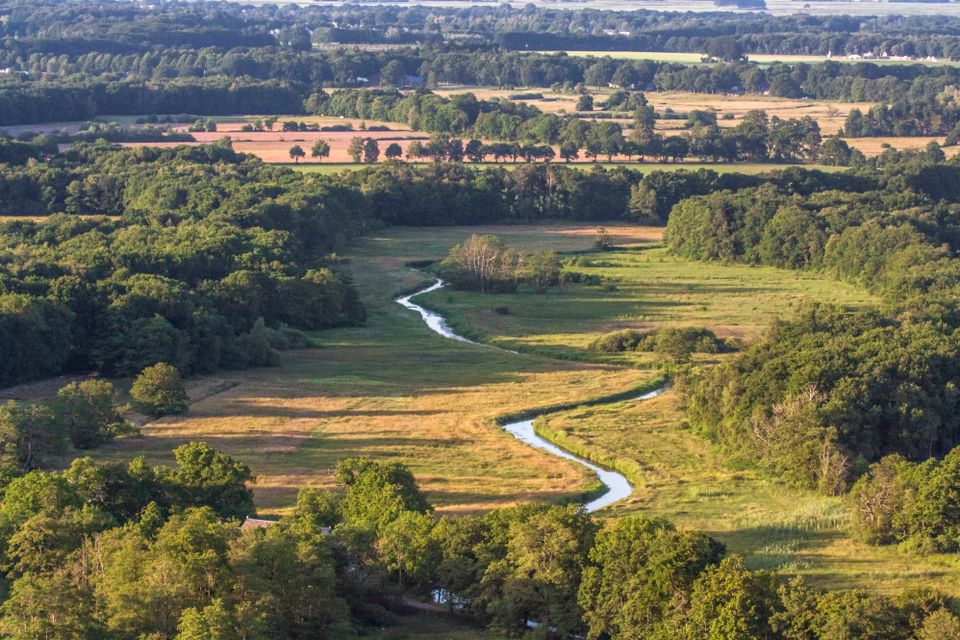 Eine Luftaufnahme eines sich schlängelnden Bachs, der durch Drenthe fließt.